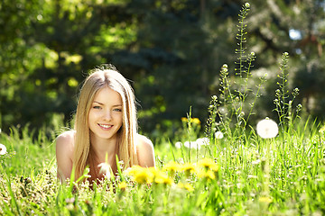 Image showing Spring girl lying on the field of dandelions