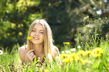 Image showing Spring girl lying on the field of dandelions