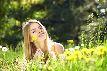 Image showing Spring girl lying on the field of dandelions