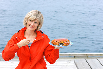 Image showing Happy woman holding cooked crab on white plate