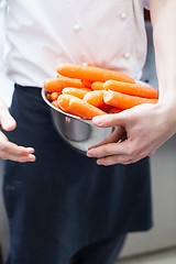 Image showing Chef in uniform preparing fresh carrot batons