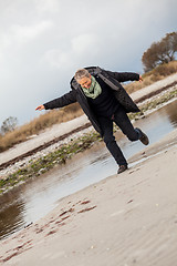 Image showing Happy senior woman frolicking on the beach