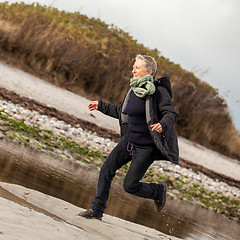 Image showing Happy senior woman frolicking on the beach