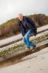 Image showing Elderly energetic man running along a beach