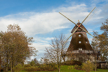 Image showing Traditional wooden windmill in a lush garden