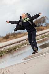 Image showing Happy senior woman frolicking on the beach