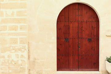 Image showing Arched wooden door in a stone wall