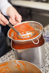 Image showing Woman chef whisking boiled tomato sauce in a pot