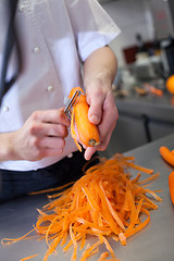 Image showing Chef in uniform preparing fresh carrot batons