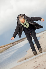 Image showing Happy senior woman frolicking on the beach