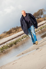 Image showing Elderly energetic man running along a beach