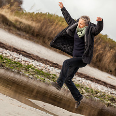 Image showing Happy senior woman frolicking on the beach