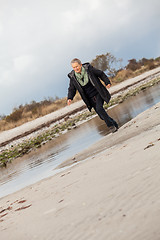 Image showing Happy senior woman frolicking on the beach