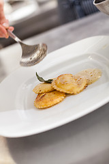 Image showing Chef grating truffle mushroom onto ravioli pasta