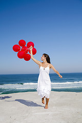 Image showing Beautiful girl running with red ballons