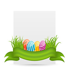 Image showing Easter colorful eggs in green grass with empty paper card for yo