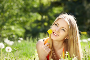 Image showing Spring girl lying on the field of dandelions