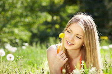 Image showing Spring girl lying on the field of dandelions