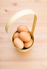 Image showing Brown egg in bucket with wooden background