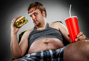 Image showing Fat man eating hamburger