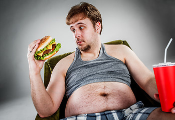 Image showing Fat man eating hamburger