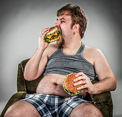 Image showing Fat man eating hamburger