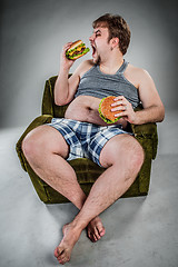 Image showing Fat man eating hamburger