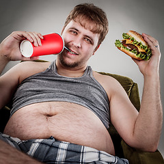 Image showing Fat man eating hamburger