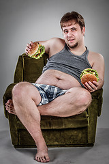 Image showing Fat man eating hamburger