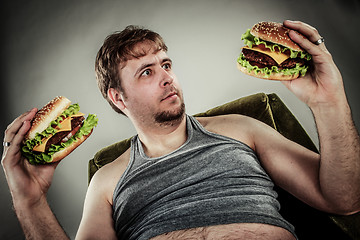 Image showing Fat man eating hamburger