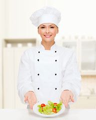 Image showing smiling female chef with salad on plate