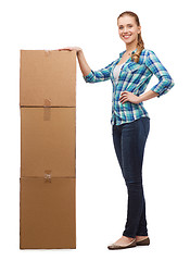 Image showing young woman standing next to tower of boxes