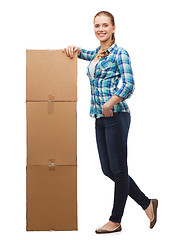 Image showing young woman standing next to tower of boxes