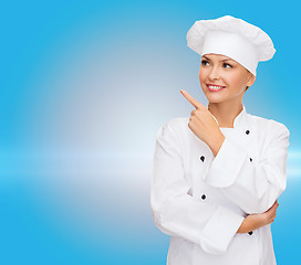 Image showing smiling female chef pointing finger to sonething