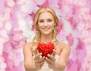 Image showing smiling woman giving small red heart