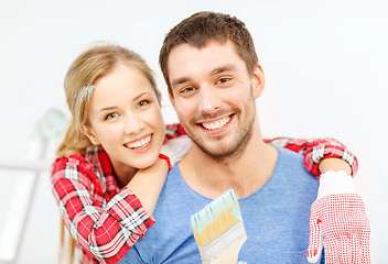 Image showing smiling couple covered with paint with paint brush