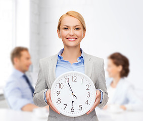 Image showing smiling businesswoman with wall clock