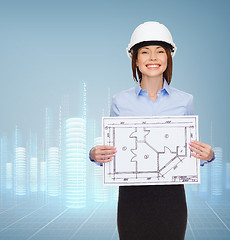 Image showing smiling businesswoman in helmet showing blueprint