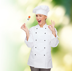 Image showing smiling female chef with fork and tomato