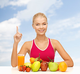 Image showing woman with juice and fruits holding finger up