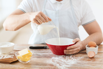 Image showing close up of male hand pouring milk in bowl