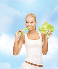 Image showing smiling woman biting lettuce