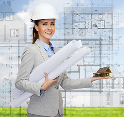 Image showing smiling architect in white helmet with blueprints