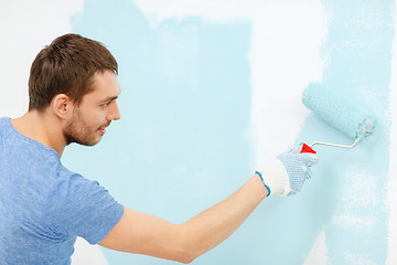 Image showing smiling man painting wall at home