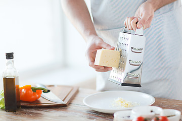 Image showing close up of male hands grating cheese