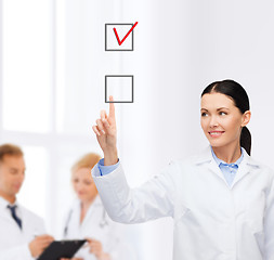 Image showing smiling female doctor pointing checkbox