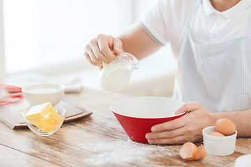 Image showing close up of male hand pouring milk in bowl