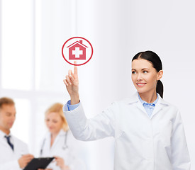 Image showing smiling female doctor pointing to hospital sign