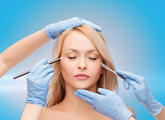 Image showing woman and beautician hands with pencil and scalpel