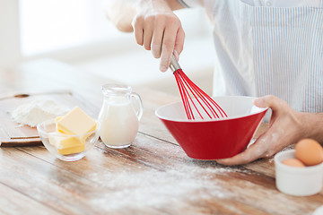 Image showing close up of male hand whisking something in a bowl
